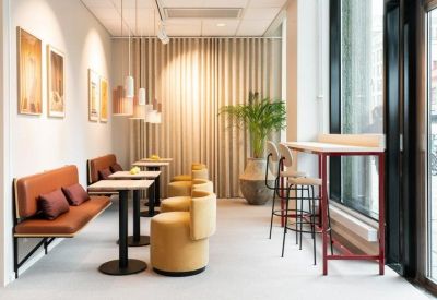 Bright coworking area with leather banquette seating and pendant lights.