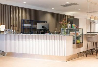 Sleek white reception counter with wood-slat backdrop and bar stools.
