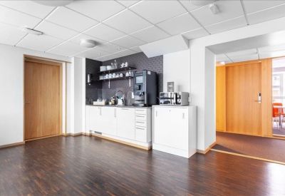 Clean communal kitchen area with a professional coffee machine and wooden floors.