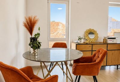 Small round meeting table by a window overlooking red-tiled rooftops.