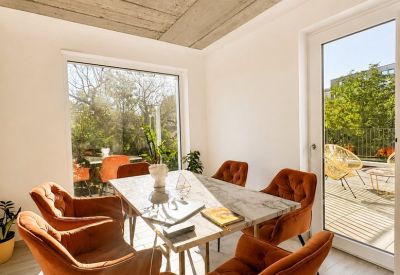 Sunny dining area with orange chairs and glass door leading to an outdoor terrace.