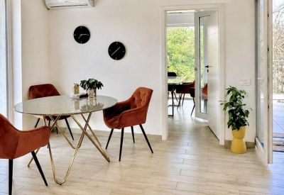 Bright workspace with round marble table, orange chairs, and a potted plant.