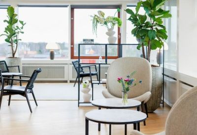 Casual seating area with comfortable grey armchairs, coffee tables, and indoor plants.