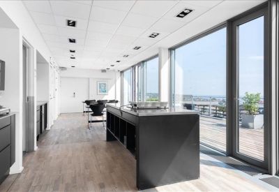 Bright communal kitchen area with a large black island and terrace access.