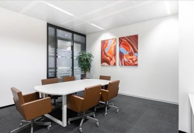 Modern conference room with an oval white table, brown leather chairs, and abstract art.
