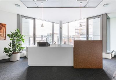 Professional reception area with a white desk and a large indoor plant.