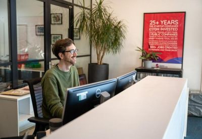 Modern reception desk featuring a green sweater-clad staff member and a large red information poster.