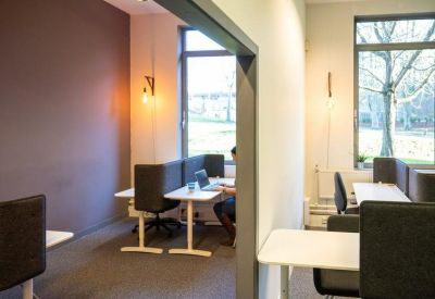 Cozy workspace with private desks separated by grey acoustic panels and warm pendant lighting.