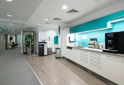 Communal kitchen and breakout area featuring vibrant teal cabinetry and a coffee station.