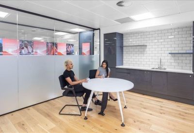 Modern kitchen and breakout area with a round white table, grey cabinetry, and subway tile backsplash.