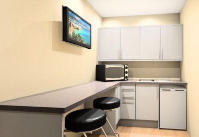 Modern communal kitchen and breakout area with a breakfast bar, stools, and white cabinetry.