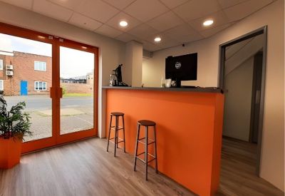 Bright reception area featuring a vibrant orange front desk and wood-effect flooring.