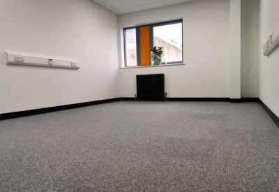 Spacious private office suite with grey carpeting and a large window providing natural light.