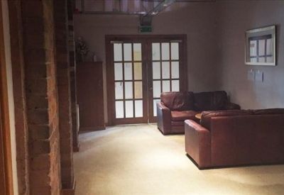 Communal lounge area with comfortable leather sofas and a glass-paneled door.