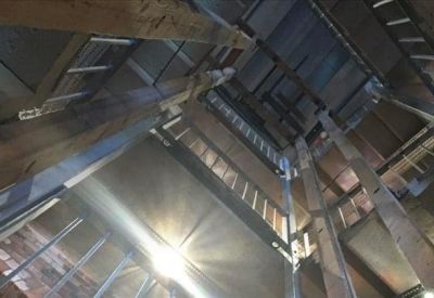 Looking up into a high-ceilinged atrium with exposed timber beams and industrial metal stairs.