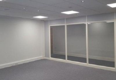 Empty office suite with grey carpeting and a glass partition wall.