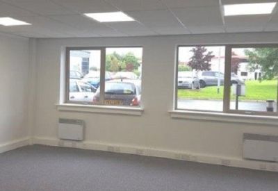 Bright office space featuring large windows and wall-mounted heaters.