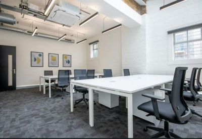 Spacious boardroom with long white tables, black mesh chairs, and large windows.