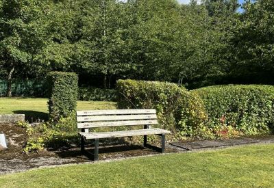 Tranquil outdoor break area featuring a wooden bench and manicured greenery.