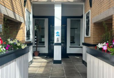 Bright entrance foyer featuring a glass ceiling and white wood-paneled walls with plants.