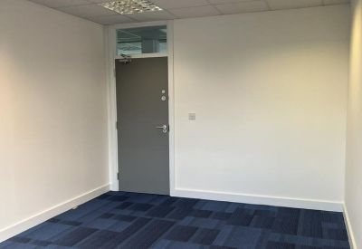 Clean, modern private office with blue carpet tiles and neutral white walls.