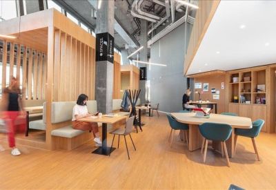 Contemporary meeting room with a large light-wood table, teal chairs, and unique pendant lighting.