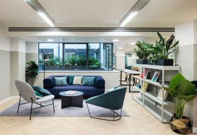 Modern lounge area with a navy sofa, stylish armchairs, and bookshelves.