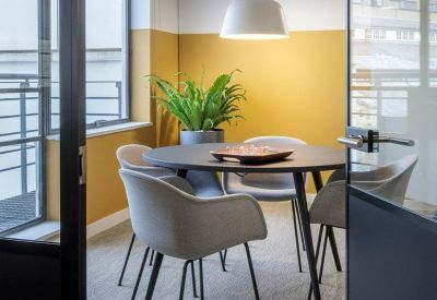 Private four-person meeting room with a round table and mustard yellow feature wall.