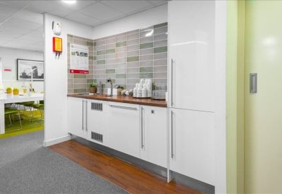 Modern communal kitchen area with white cabinetry and wooden countertops.