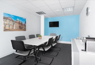 Meeting room with a large white table, black chairs, and a blue feature wall.