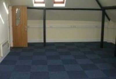 Attic office space with blue checkered carpet tiles and skylight windows.