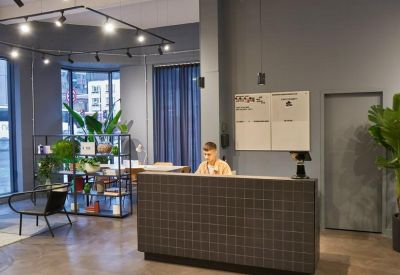 Modern reception desk with a grey tiled front and potted plants.