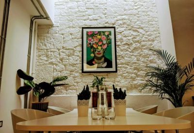 Communal dining area featuring a stone accent wall, floral artwork, and potted plants.