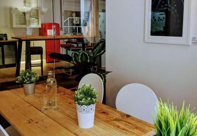 Wooden meeting table with small potted plants and white chairs in a modern office setting.