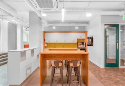 Bright communal kitchen and breakout area with high wooden tables and stools.