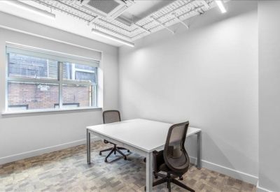 Bright two-person private office with a white desk and large window.