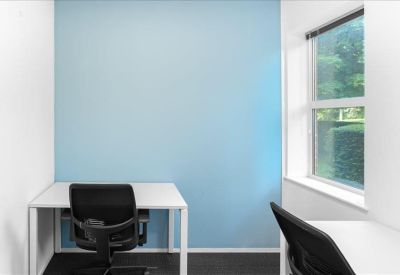 Small private office with a white desk and a blue feature wall.