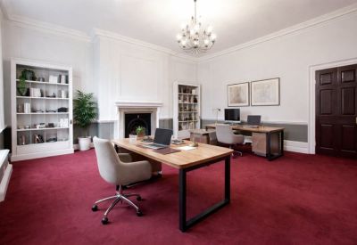 Grand private office featuring a red carpet, wooden desks, a fireplace, and a chandelier.