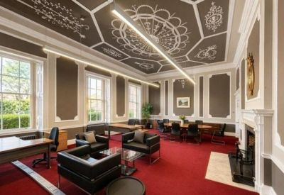 Stunning meeting room with an ornate patterned ceiling, red carpet, and large windows.