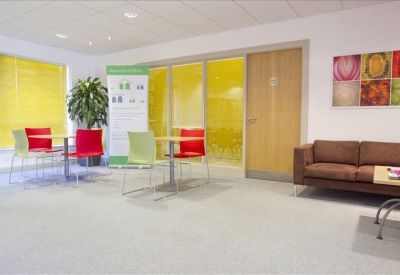 Reception and waiting area with a brown sofa, colorful wall art, and a glass-walled meeting room.