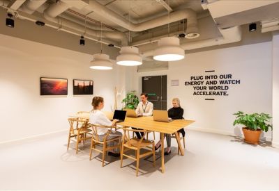 Modern workstation area with a large wooden table, designer chairs, and motivational wall art.