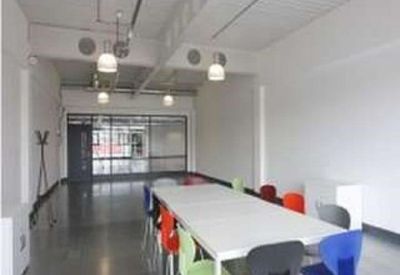 Modern meeting room with a large white table and colorful chairs.