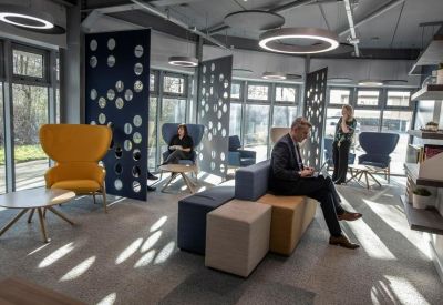 Vibrant breakout lounge featuring yellow wingback chairs and stylish blue privacy screens.