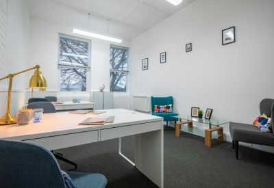 Small meeting room with a white table, gold desk lamp, and colorful accent chairs.