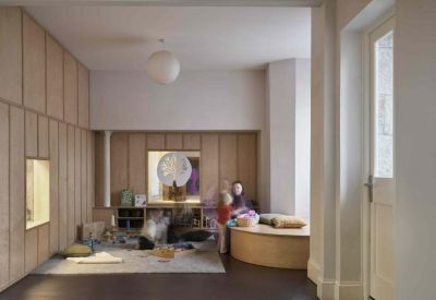 Childrens play area with wood panelled walls and soft seating.