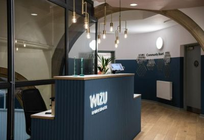 Modern reception area with a blue slatted front desk and decorative industrial hanging light bulbs.