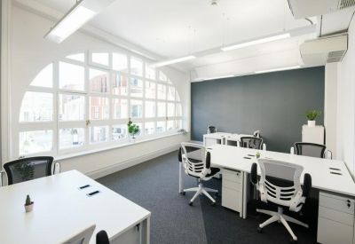 Bright office suite with white desks, ergonomic chairs, and a large arched window.