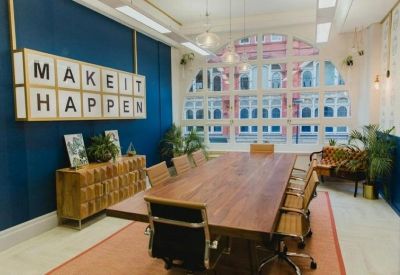Boardroom with a long wooden table, leather chairs, and a large Make It Happen wall sign.