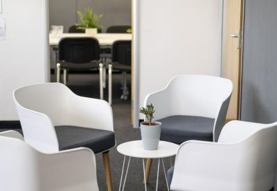 Casual breakout area with modern white armchairs and a small coffee table.