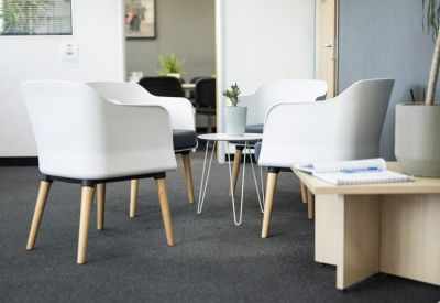 Brightly lit waiting area with white lounge seating and a leafy green plant.